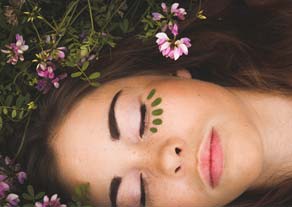 ladys face with eyes closed amidst flowers